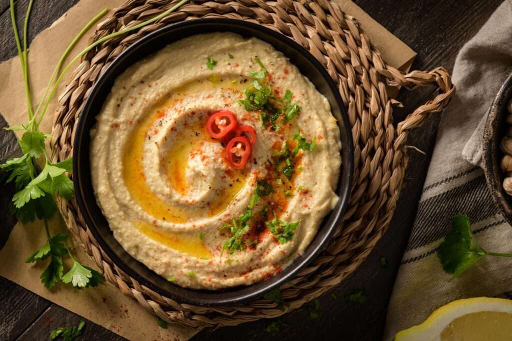 A bowl of hummus on a wooden table.