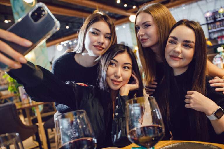 A group of friends capturing a selfie during daylight in a restaurant.
