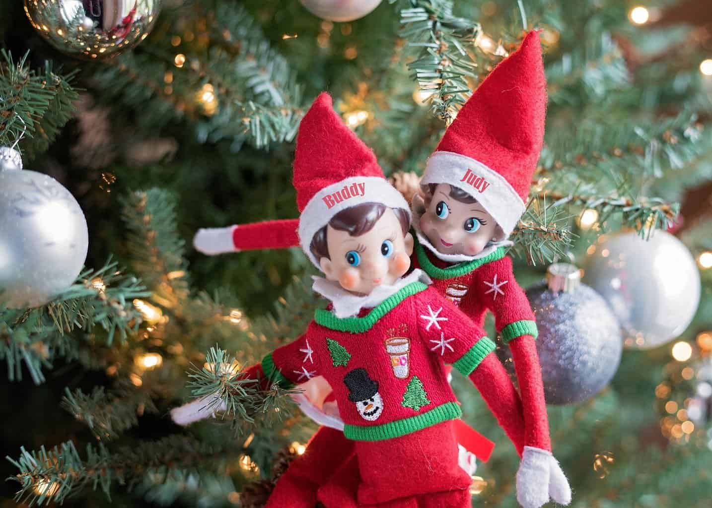 Two elf dolls bringing cheer to a Christmas tree during the winter season.